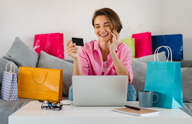 happy-smiling-woman-pink-shirt-sofa-home-colorful-shopping-bags-holding-credit-card-paying-online-laptop